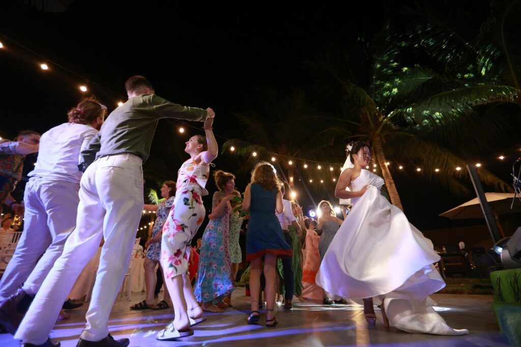 A wedding reception with guests dancing at night.