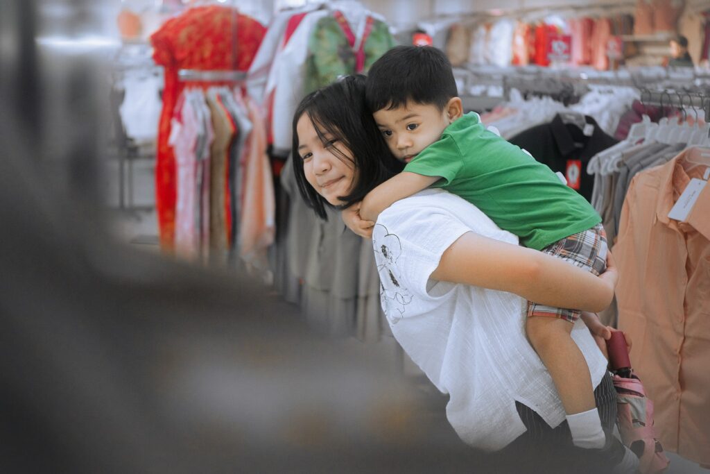 Woman giving a child a piggyback ride in a store.