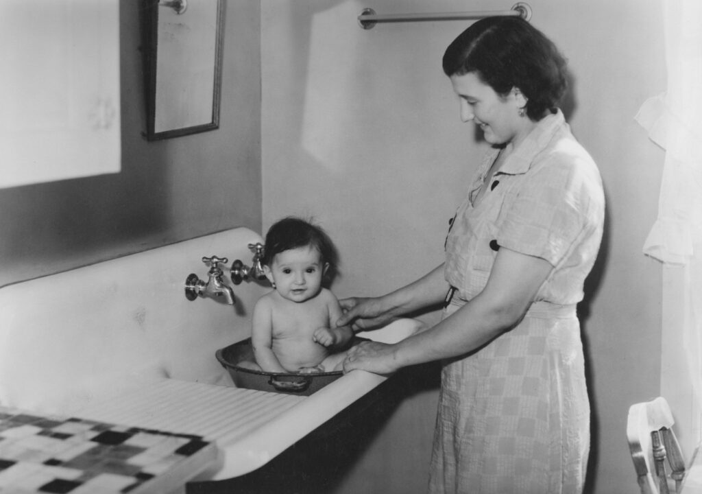 Mother bathing baby in a sink