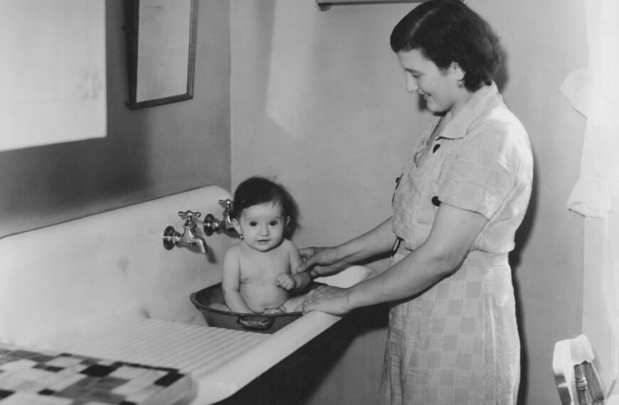 Mother bathing baby in a sink
