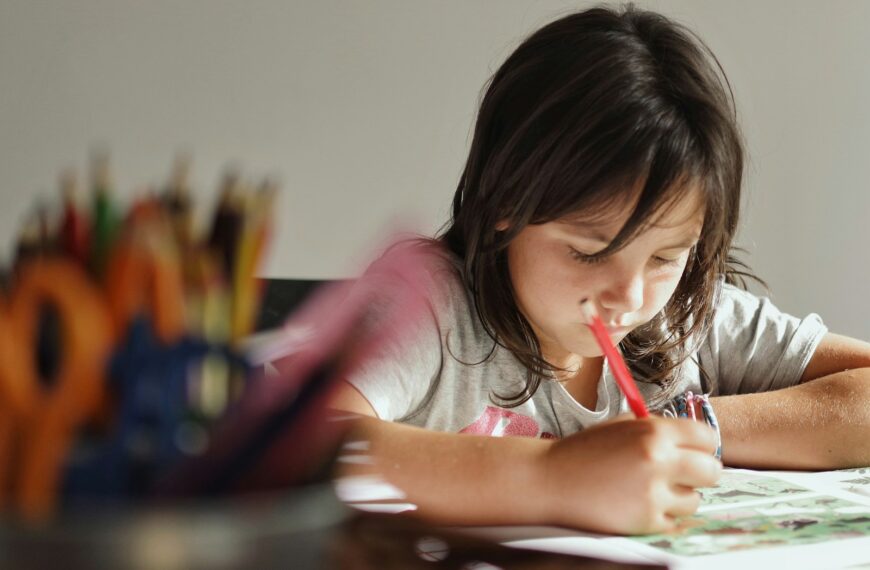 girl in pink t-shirt writing on white paper