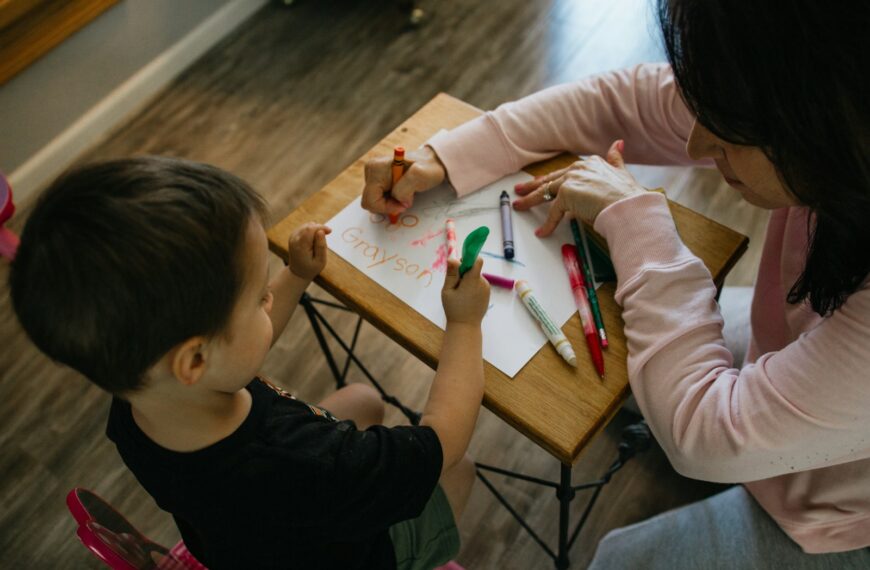 boy in white long sleeve shirt writing on white paper