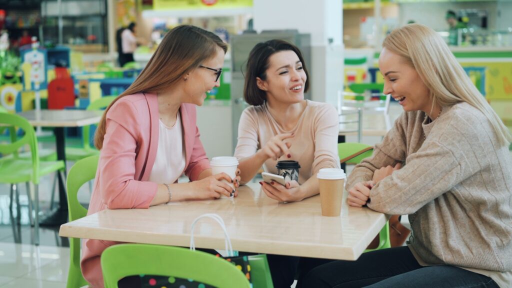 Three women laughing and talking at a table.