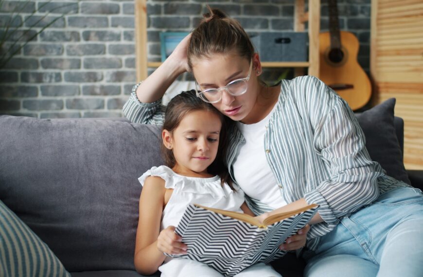 Mother and daughter reading a book together on couch