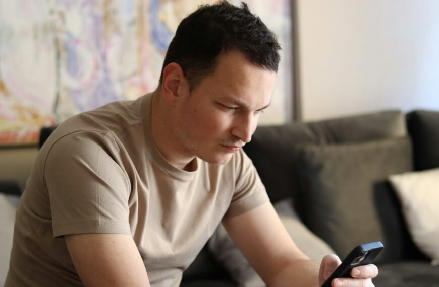a man sitting on a couch looking at his cell phone
