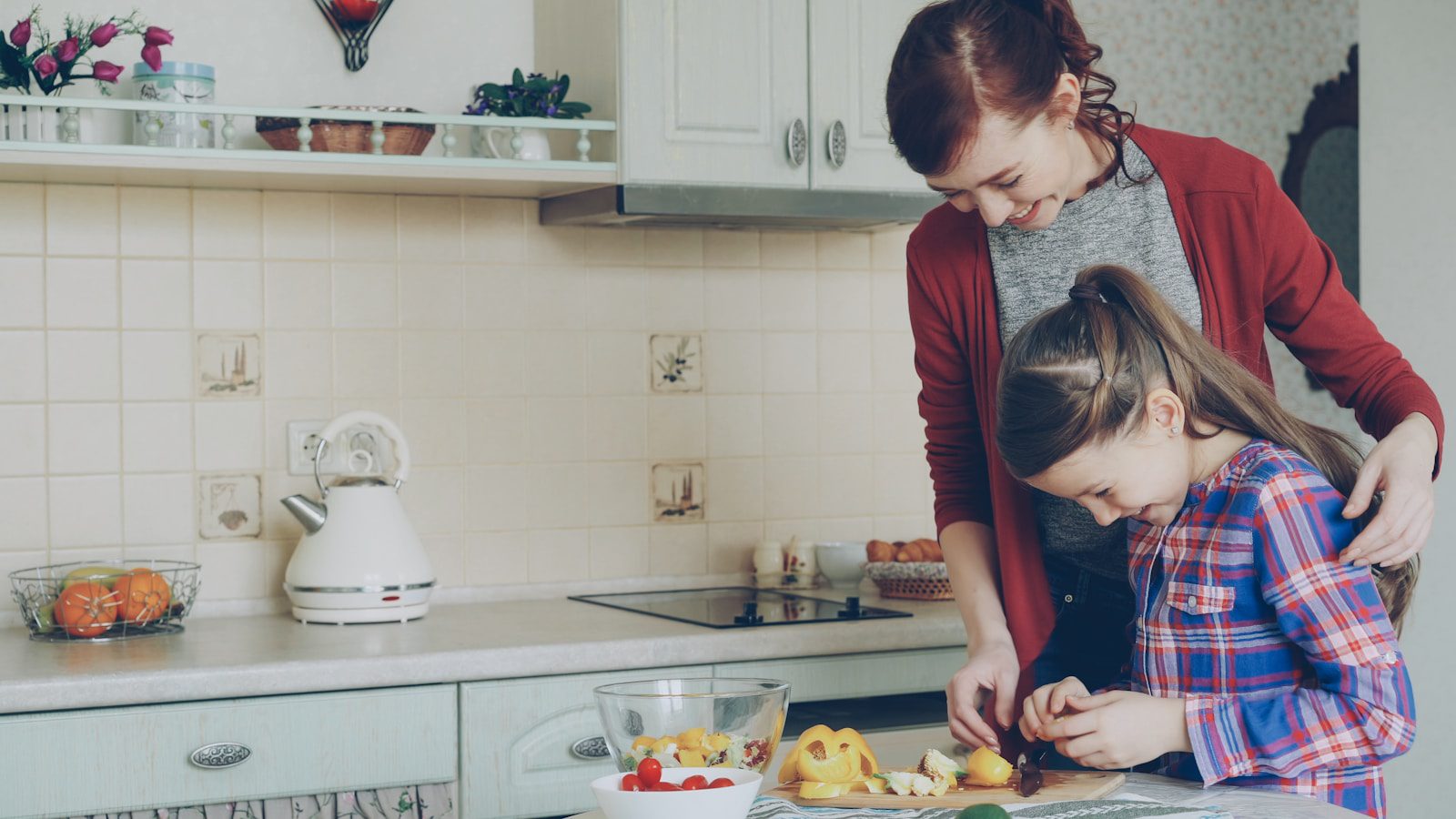 A mother and daughter cook together in the kitchen.