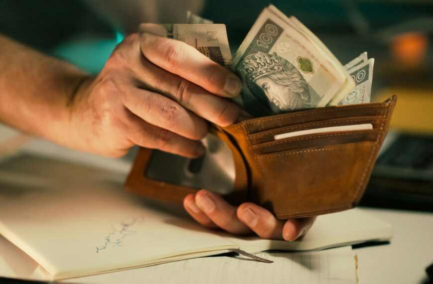 Hands holding us dollar bills in a brown leather wallet