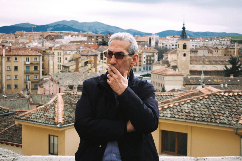 Man smoking a cigarette with city in background
