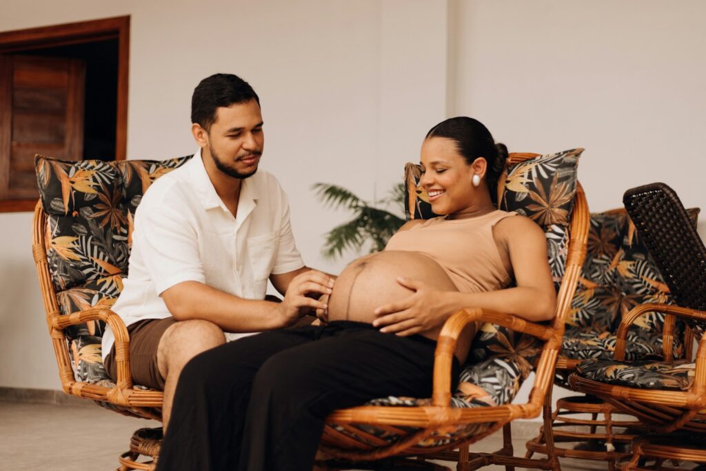 a pregnant woman sitting on a chair next to a man