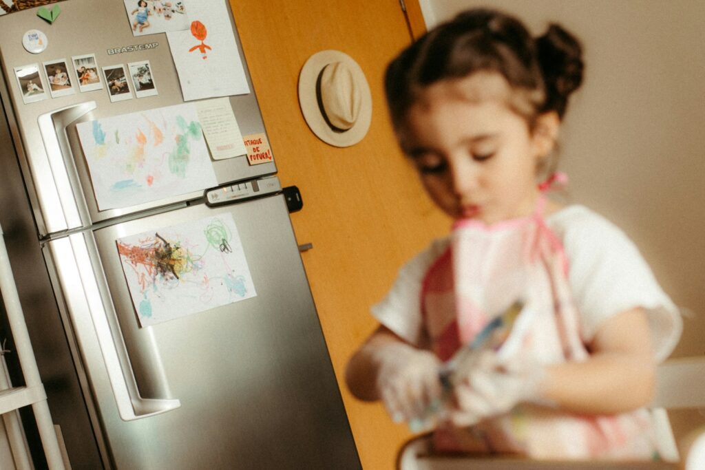 Young girl wearing an apron washes hands at sink.