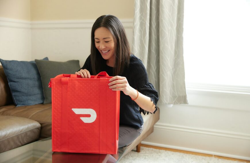 a woman sitting on a couch holding a red bag