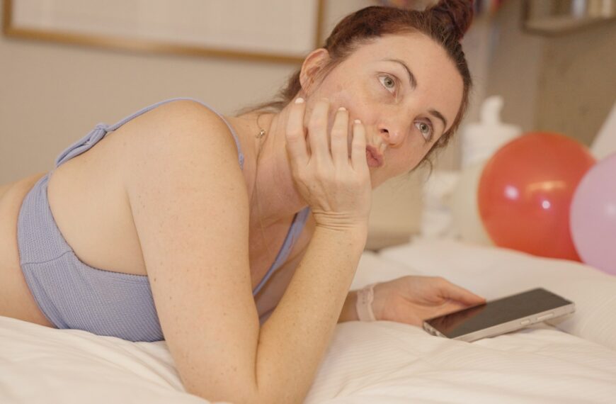 Woman lying on bed with phone and balloons