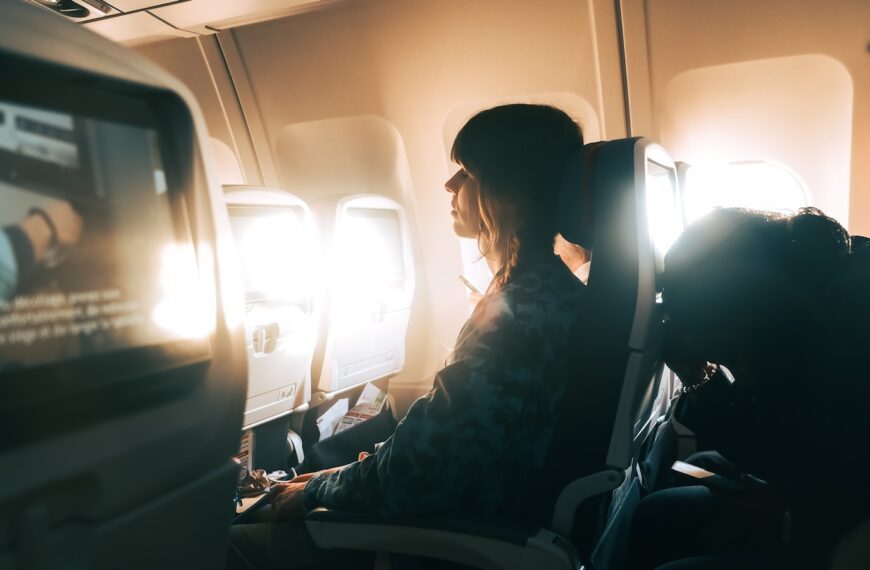 Woman looking out airplane window during flight.