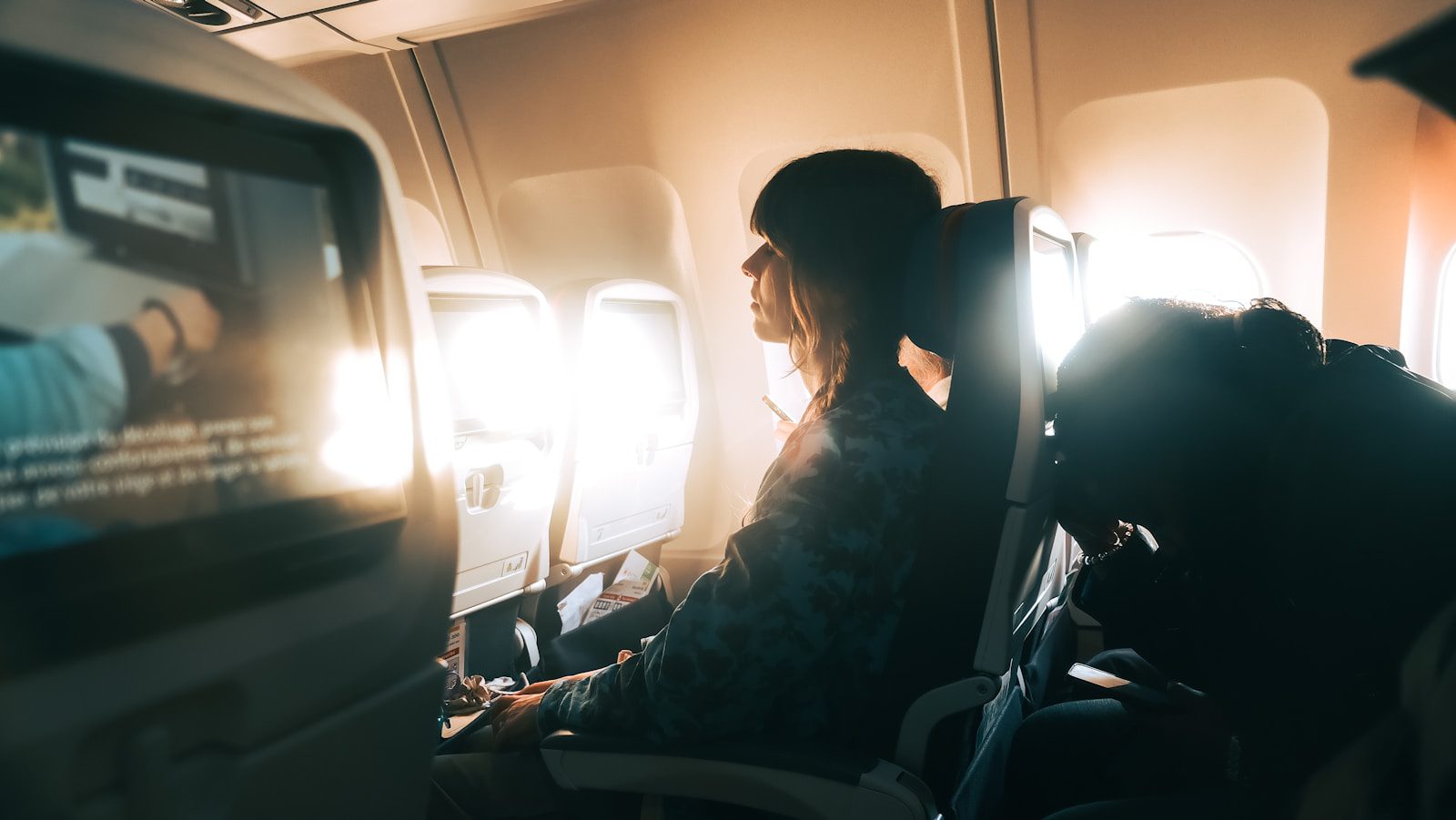 Woman looking out airplane window during flight.