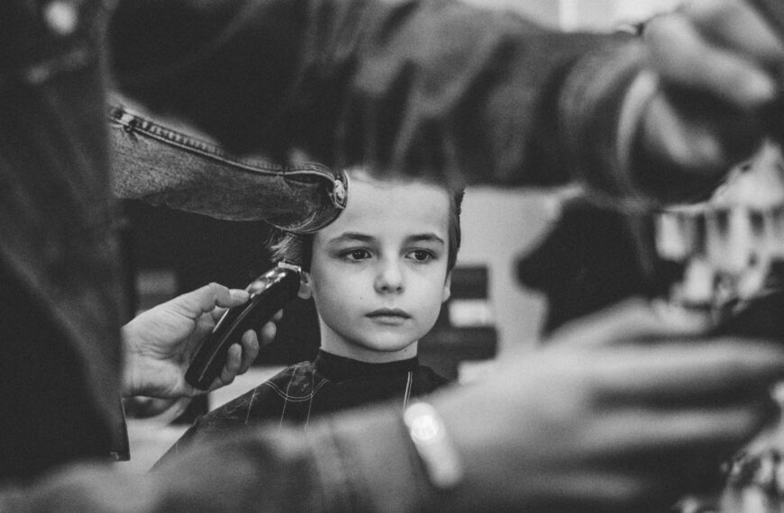 grayscale photo of boy having haircut