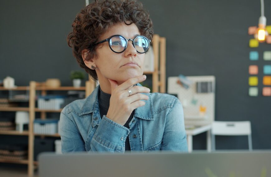 Woman wearing glasses thinking at desk