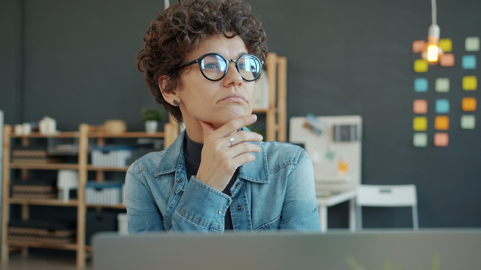 Woman wearing glasses thinking at desk