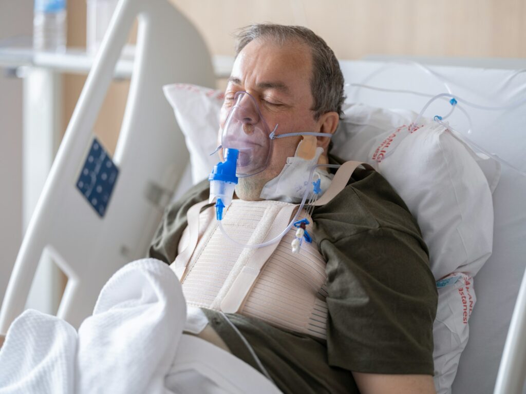 a man laying in a hospital bed with oxygen in his mouth