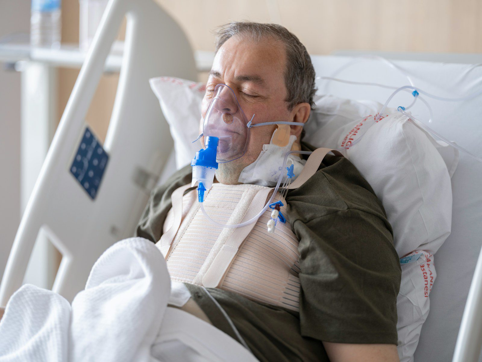 a man laying in a hospital bed with oxygen in his mouth
