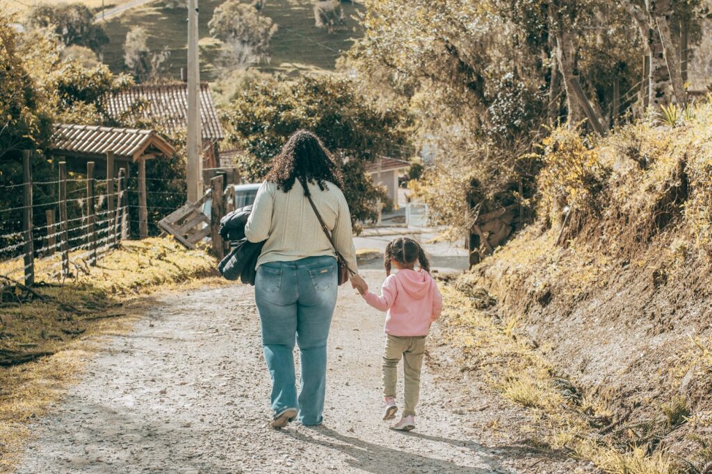 a woman and child walking down a dirt road