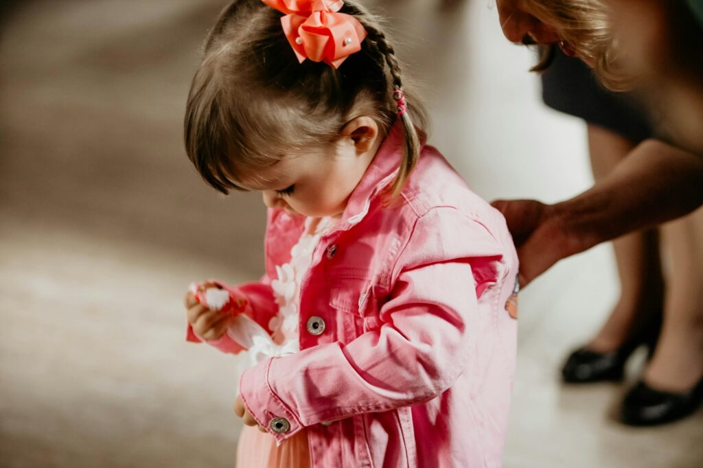 a little girl in a pink coat holding a candy