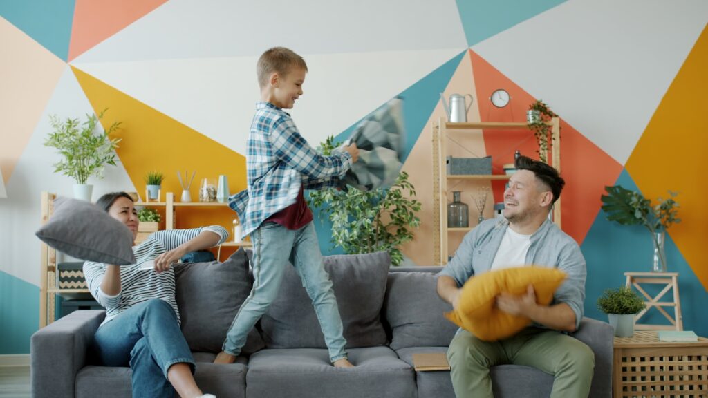 Family having a pillow fight on the couch.