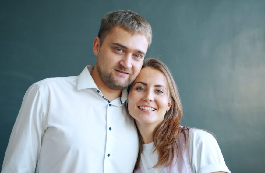 A couple smiling together against a dark background