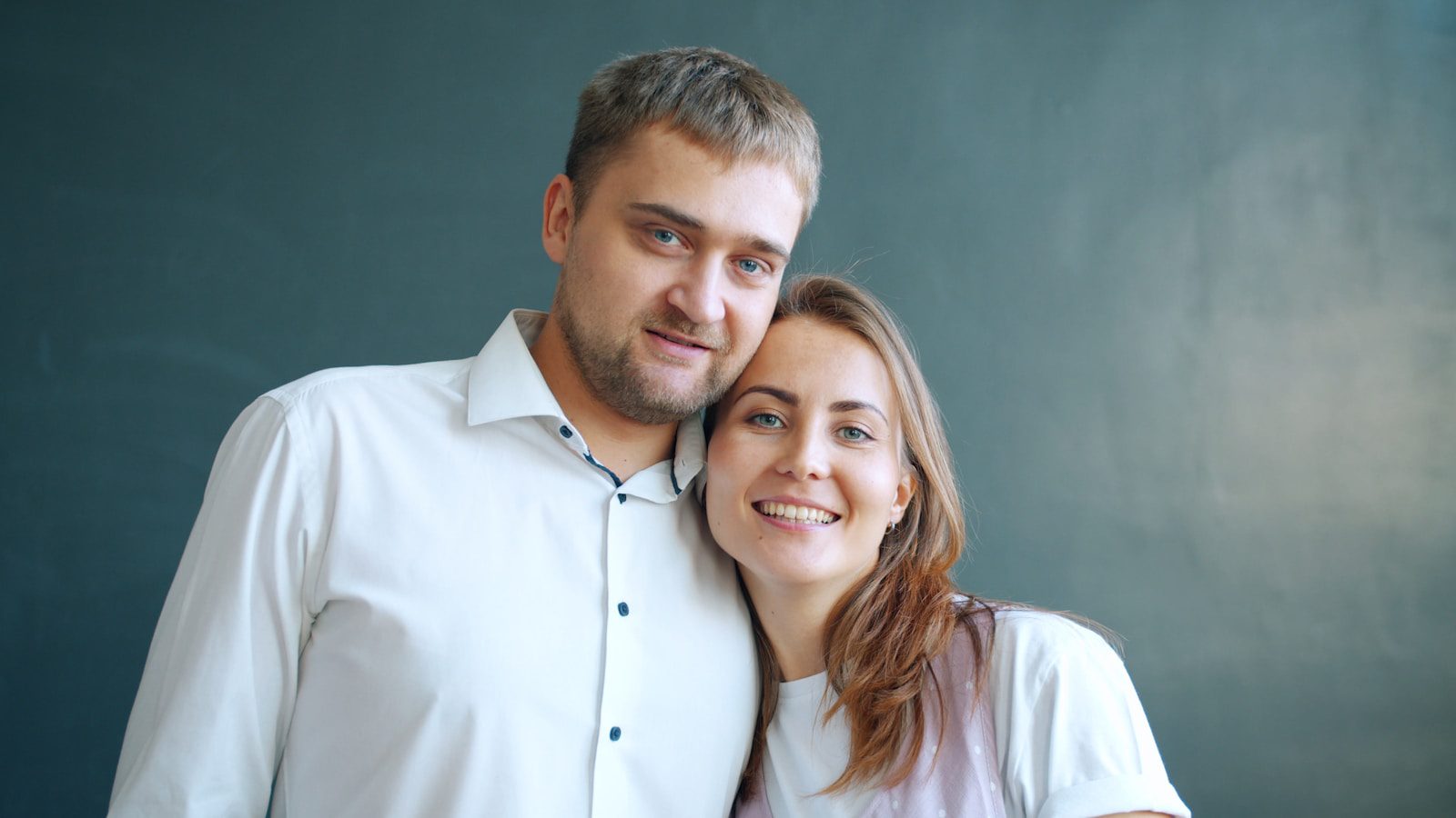 A couple smiling together against a dark background
