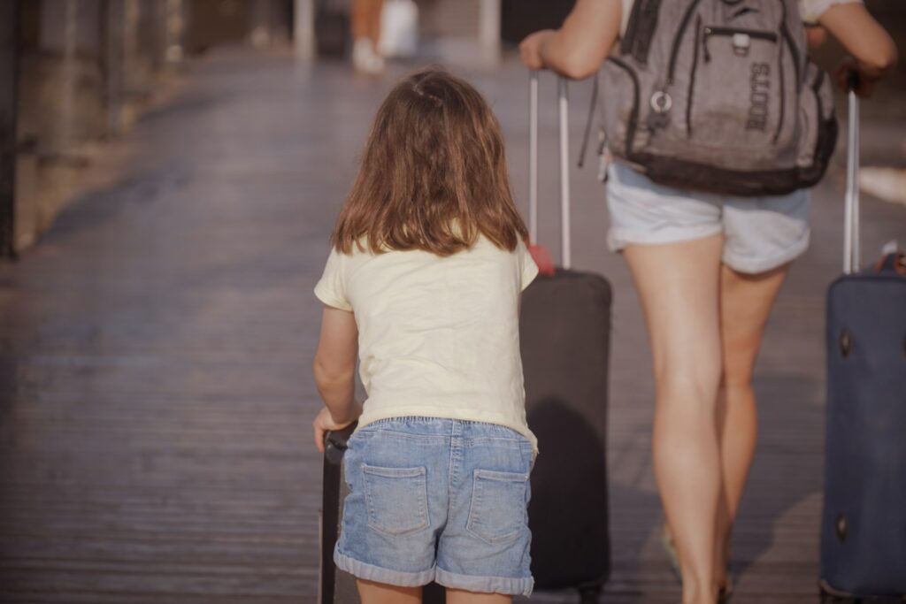 A woman and a child walking down a sidewalk with luggage