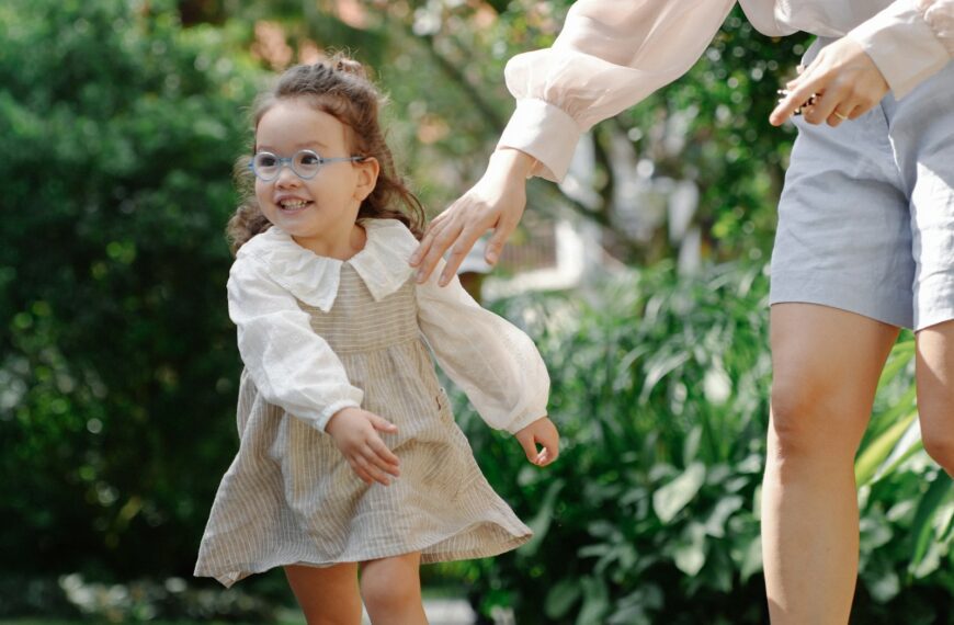 A young girl with a parent in a park