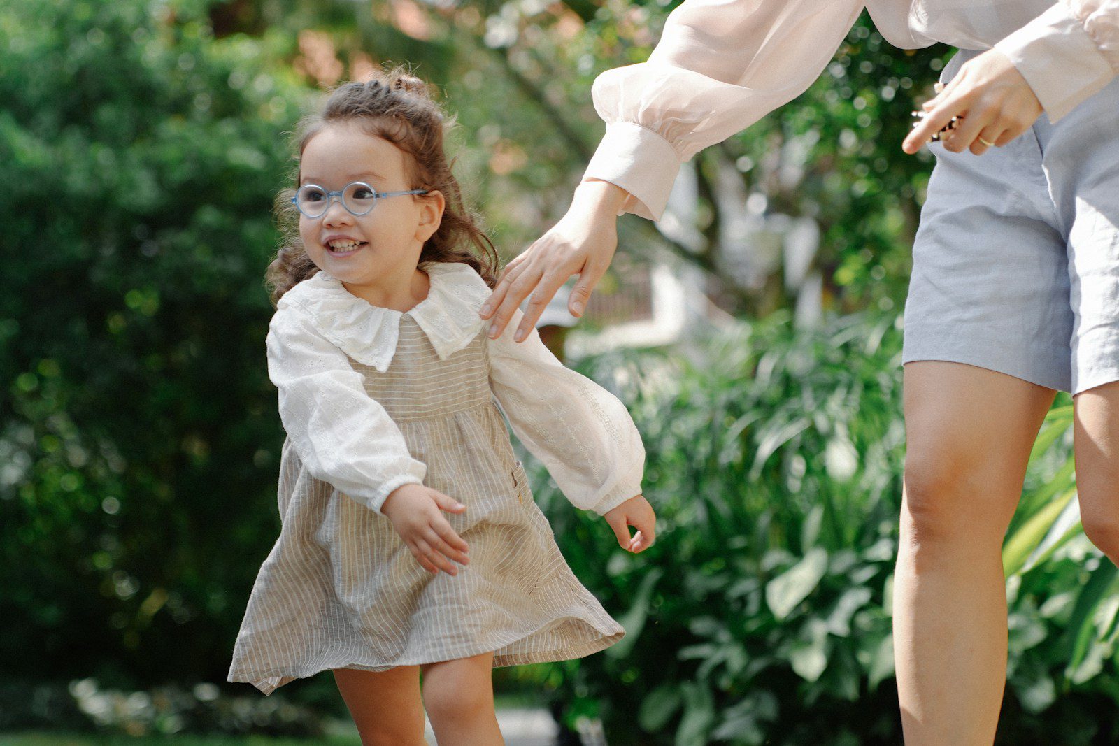 A young girl with a parent in a park
