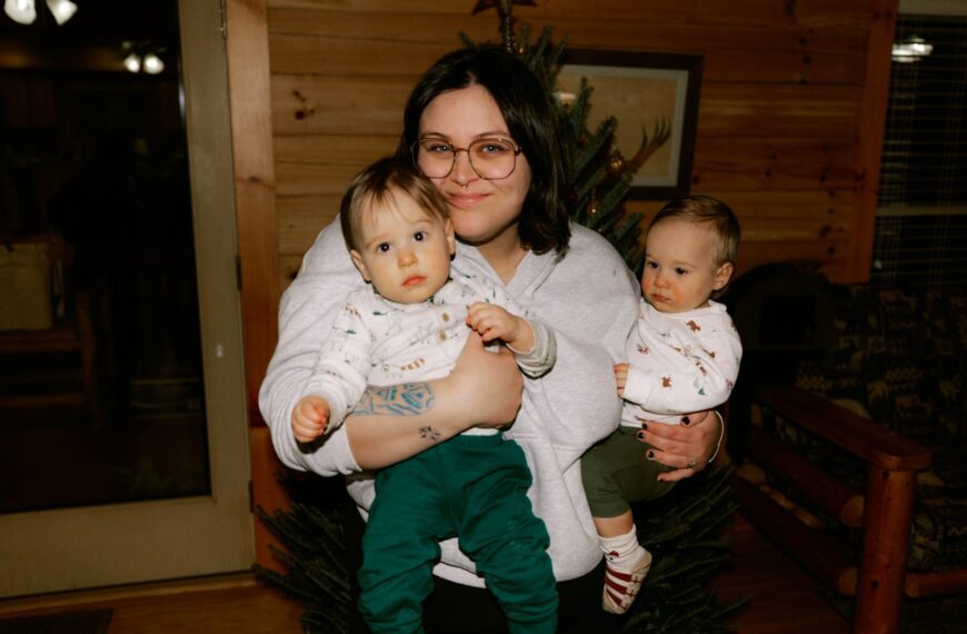Woman holding two babies in a room