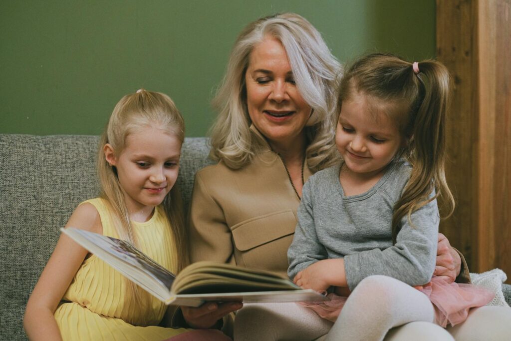 Grandmother reading a book with two granddaughters, creating a cozy family moment.