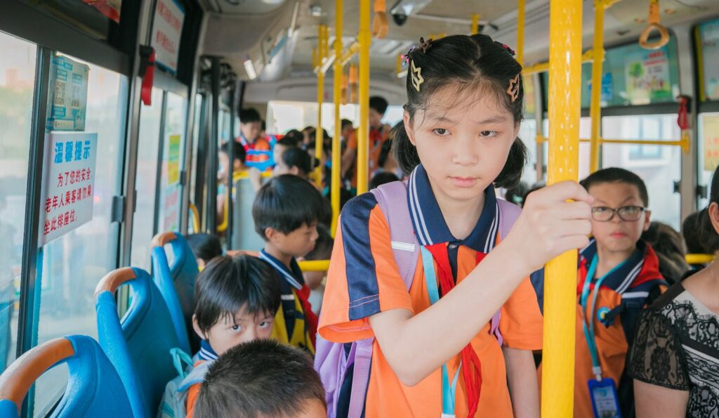 Asian schoolchildren wearing uniforms riding a bus together, traveling to class.