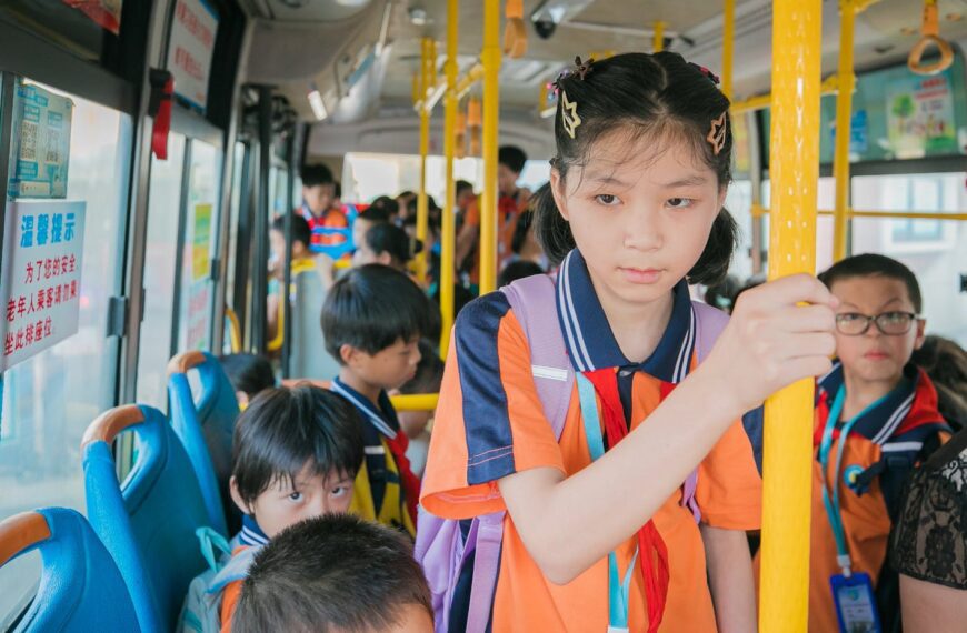 Asian schoolchildren wearing uniforms riding a bus together, traveling to class.