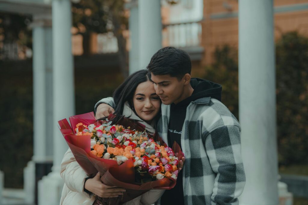 A couple shares a tender embrace holding a vibrant bouquet of flowers, symbolizing love and affection.