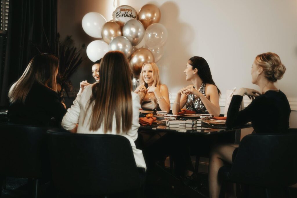 Group of women enjoying a birthday party with balloons inside. Lively and warm atmosphere.