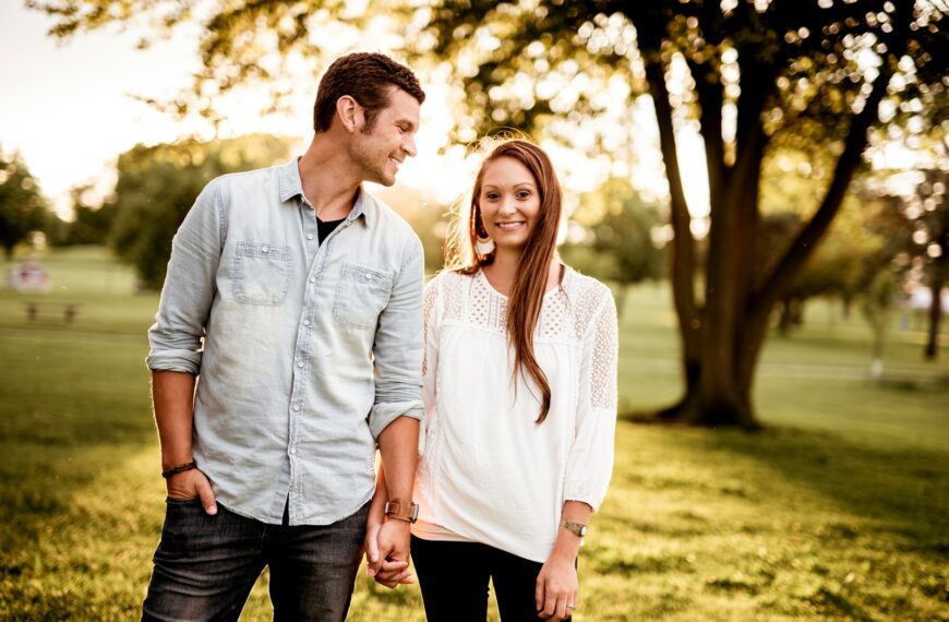 man holding hand of woman standing near tree
