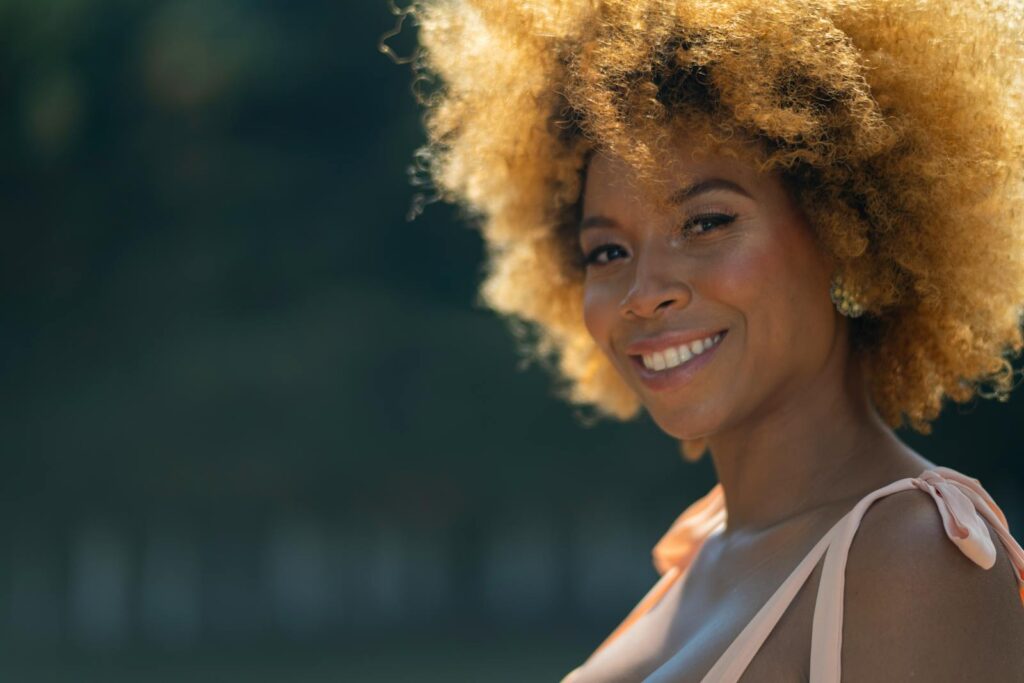 A beautiful woman with afro hair smiling outdoors in Mexico City. Warm and vibrant vibe.