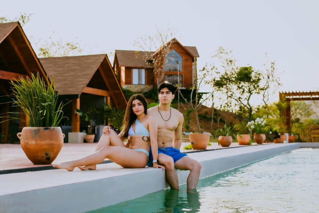 A young couple enjoys leisure time by the poolside at a luxurious resort, embracing the serene summer atmosphere.
