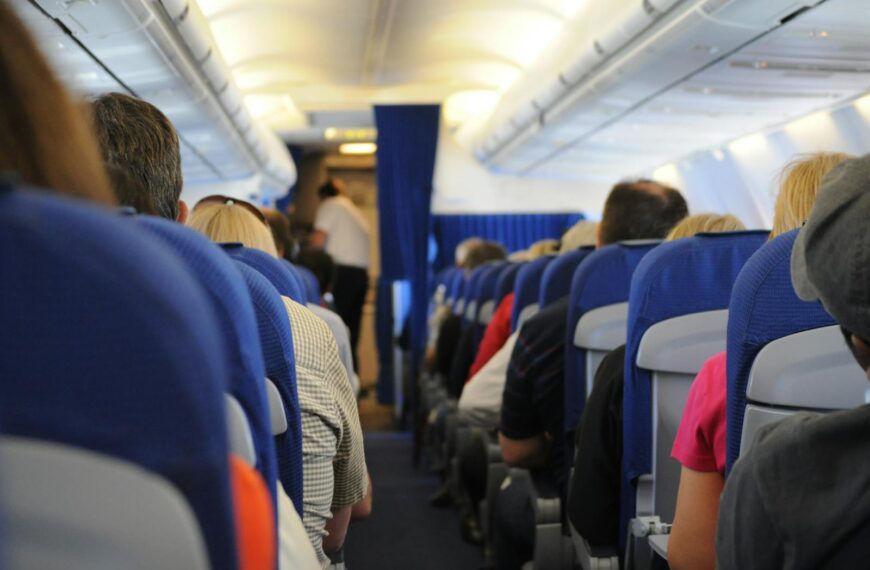Interior view of an airplane cabin with passengers seated, showcasing air travel experience.