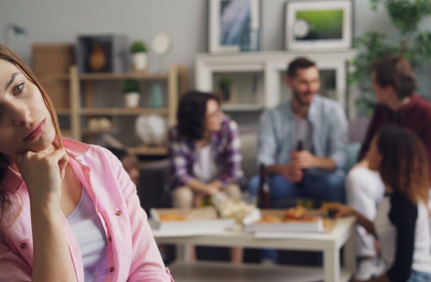 A young woman looks lonely at a party while others engage in conversation.