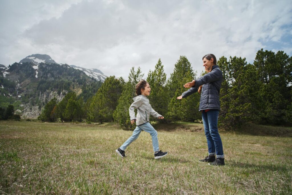 A joyful moment between mother and child in the mountains, surrounded by greenery.