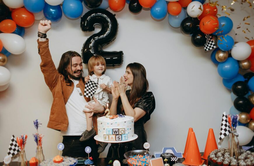 Happy family celebrating a child's second birthday with cake and decorations.