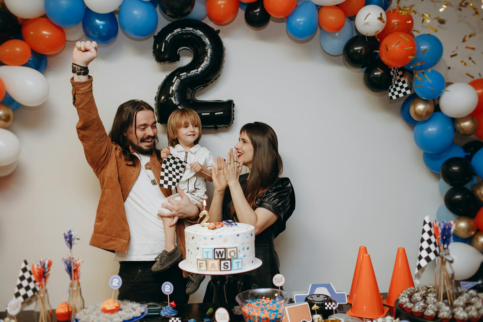 Happy family celebrating a child's second birthday with cake and decorations.