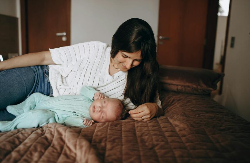 A mother lovingly watches over her sleeping newborn in a warm and intimate bedroom setting.