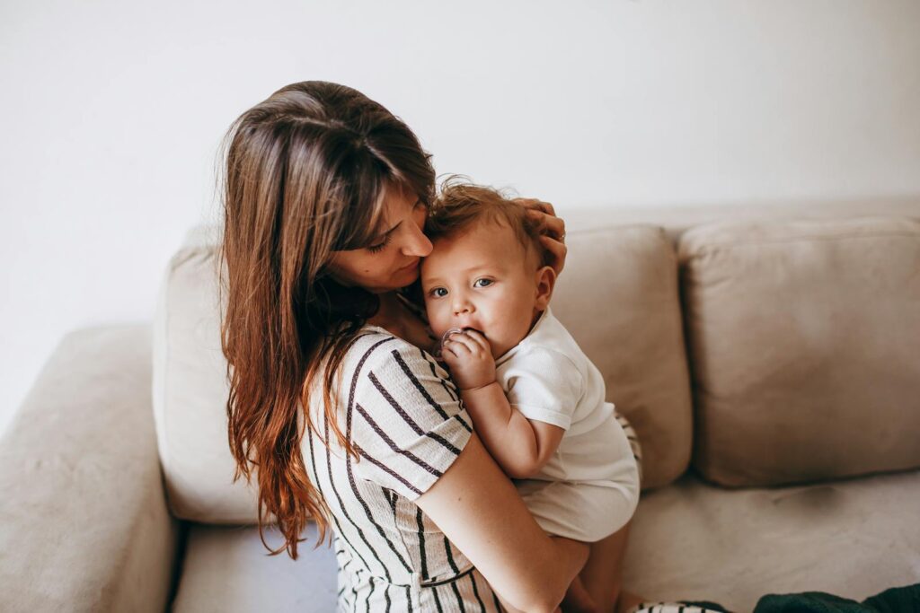 A tender moment between a mother and her baby, expressing love and warmth on a cozy home sofa.