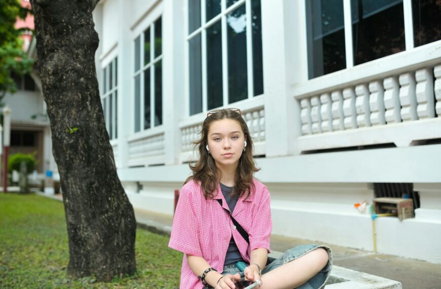 A young woman sitting casually outside a building, enjoying a moment of relaxation.