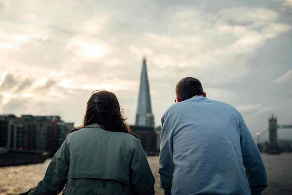 Rear view of two people overlooking London's skyline with the Shard during sunset.