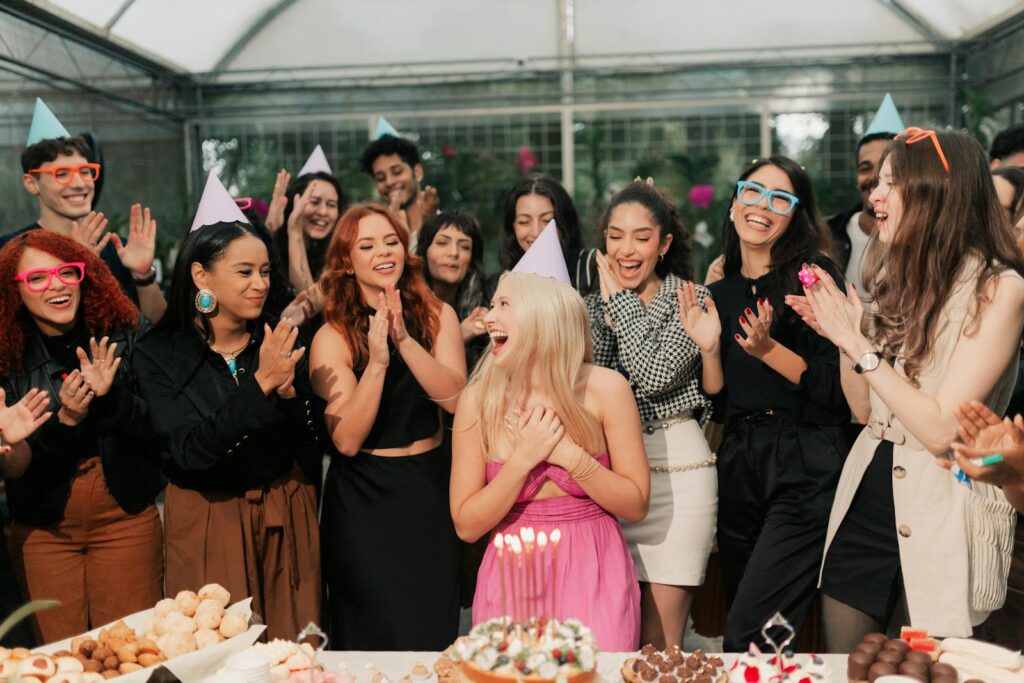 A group of friends joyfully celebrating a birthday party indoors with food and laughter.